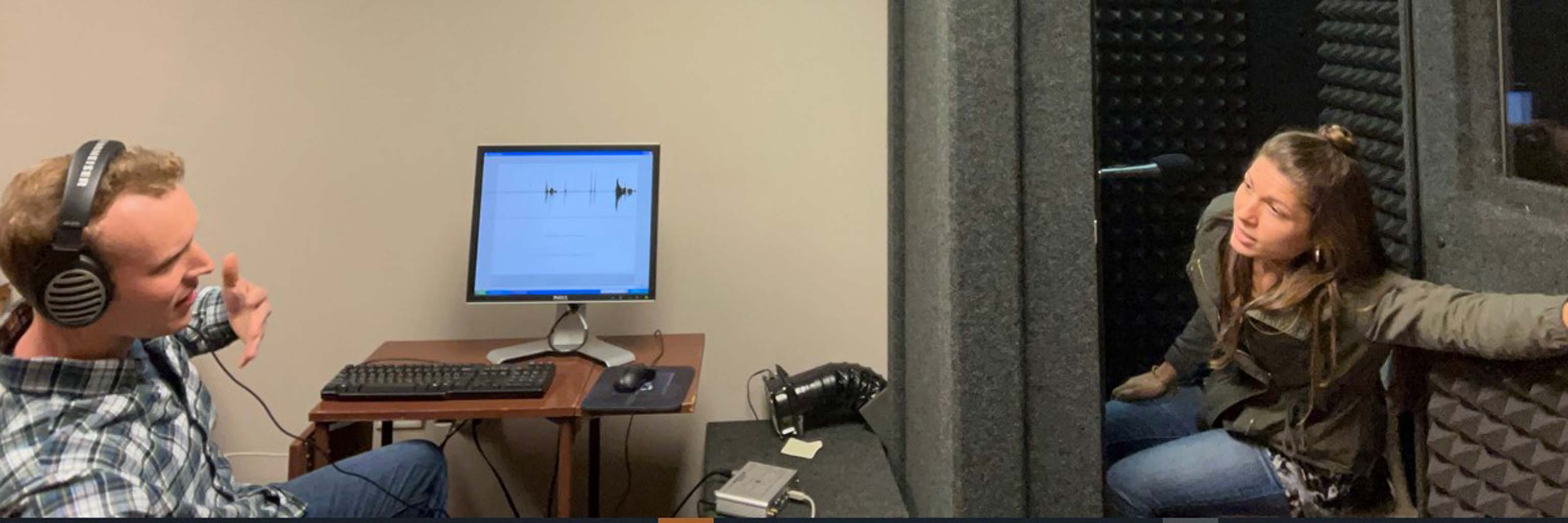 Students recording in a microphone booth